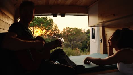 couple enjoying music in their camper van during a sunset road trip
