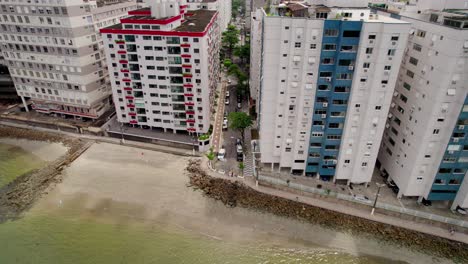 aerial shot from top to bottom through the beach towards the city buildings