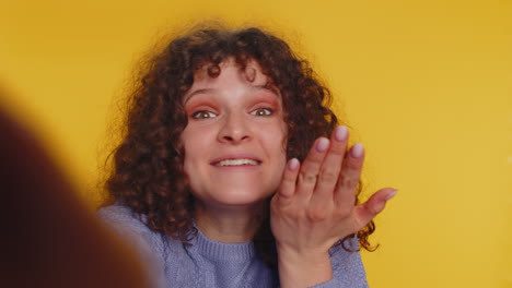 a young woman with curly hair is surprised and laughing, she is looking up and smiling with her mouth open.