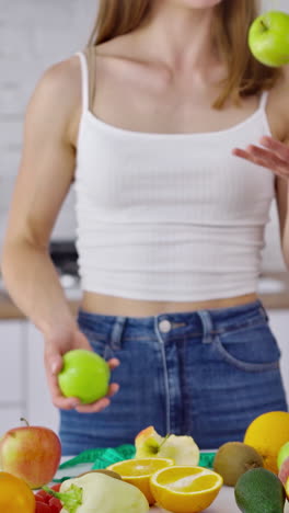 woman kitchen portrait with fruits. attractive athletic sportive woman standing in kitchen. vertical video