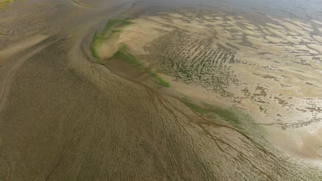 toma aérea lenta de las llanuras de marea del delta de slikken van voorne del delta del rin con arroyos y patrones grabados en la arena por la acción de las mareas