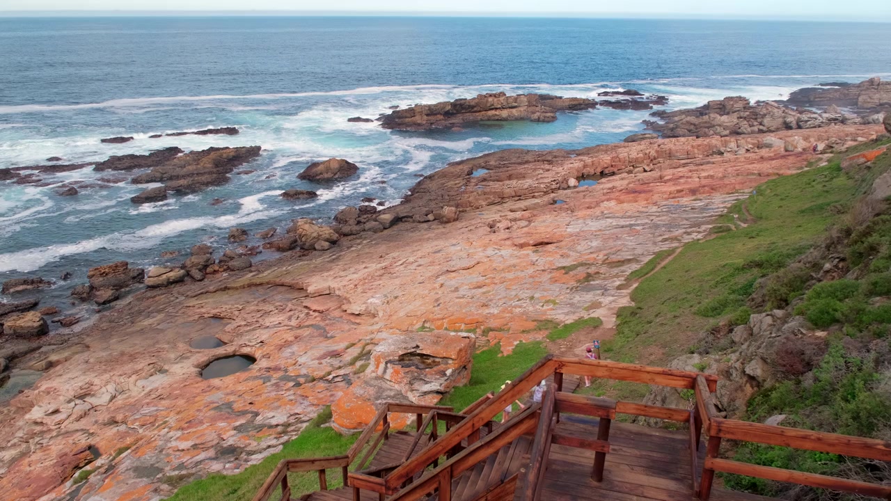 Escursionisti scendono scale di legno lungo il sentiero escursionistico della Riserva Naturale di Robberg
