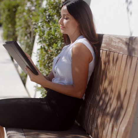 smiling young woman using her tablet outdoors