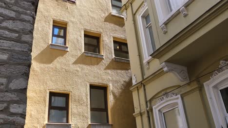 close-up of a yellow building with multiple windows and a green building with a door