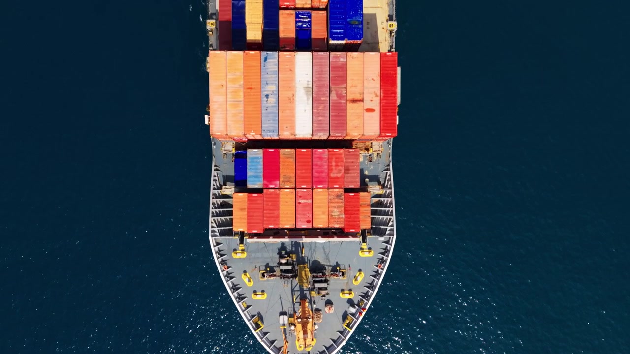 Aerial view of a cargo ship with containers navigating clear blue sea, Genoa port exit