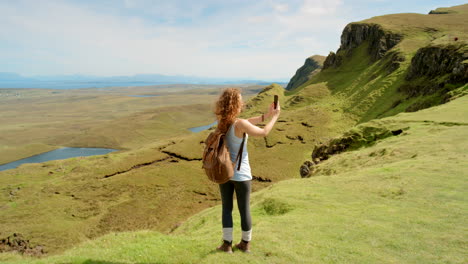 mujer tomando una foto del paisaje escénico de las tierras altas