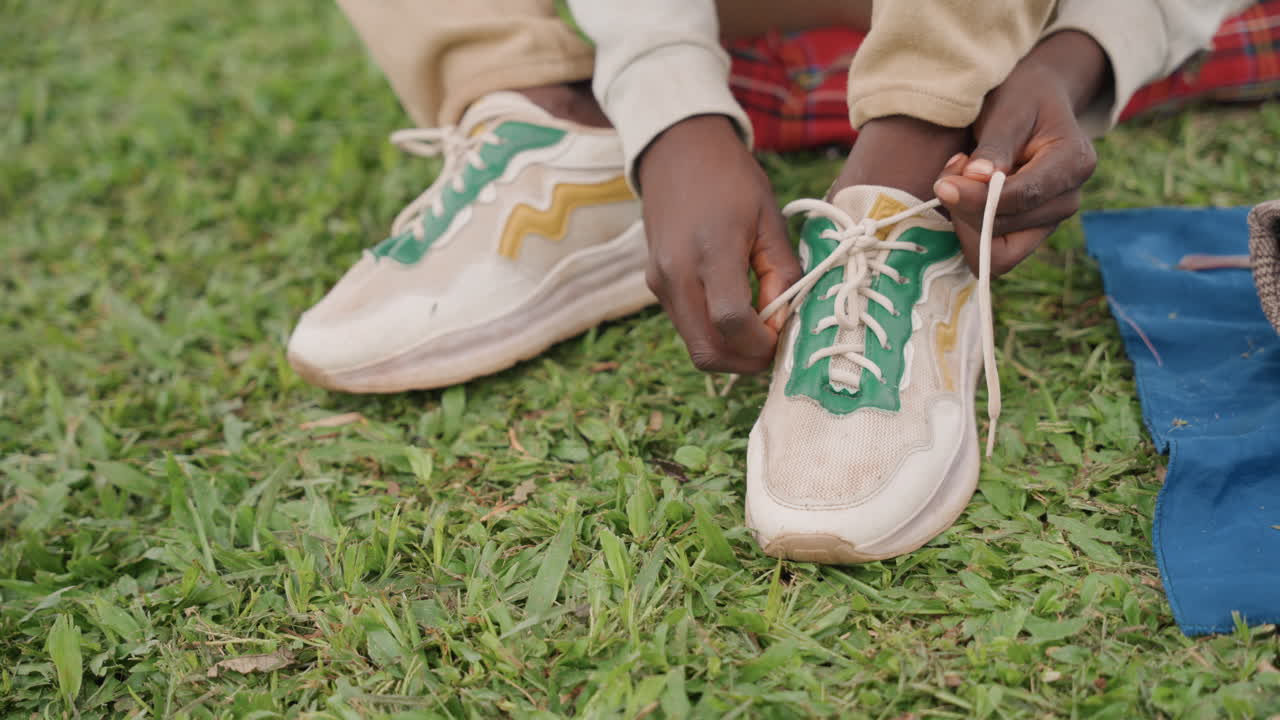 Momento di legame familiare. Il padre aiuta il figlio con le scarpe da ginnastica. Scena tenera di un padre che insegna al figlio ad allacciarsi le scarpe all'aperto. Immagine toccante di padre e figlio che si esercitano ad allacciare le scarpe in un parco.