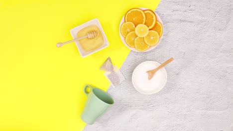 cup, tea bags, lemons, oranges, honey, sugar blinking on yellow theme. stop motion