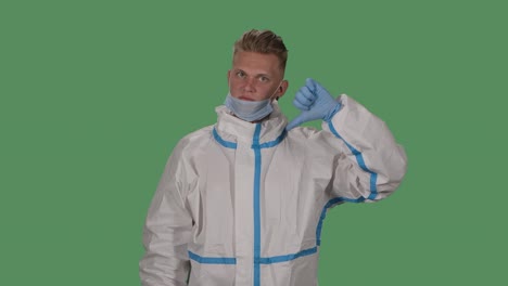 portrait of a man in a protective suit and medical mask shows walking without a mask is bad, puts on a mask and shows thumbs up and ok. green screen, chroma key. slow motion. close up