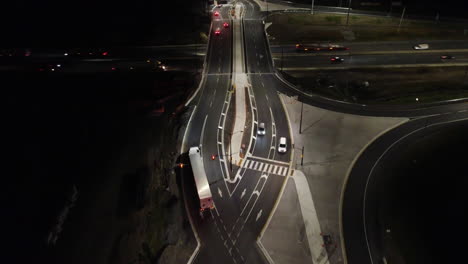 Semi-truck-driving-at-night-on-a-diamond-interchange-highway