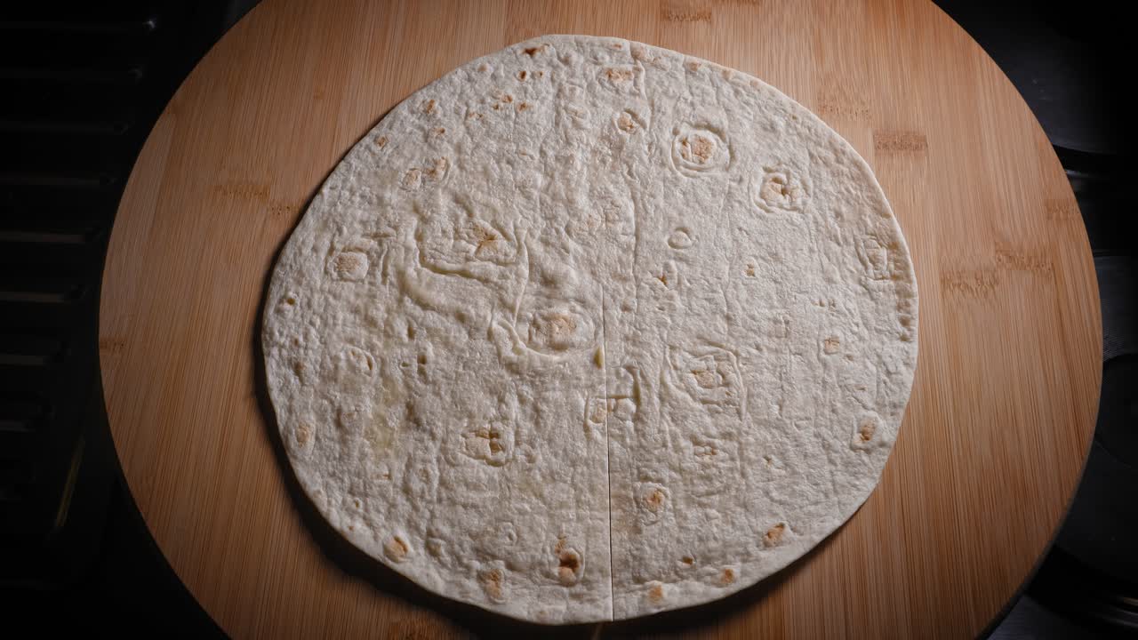 cortando la envoltura de tortilla con una rueda de pizza antes de poner huevos revueltos y champiñones y cebolla salteados para el relleno