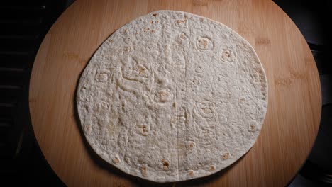 cutting tortilla wrap with a pizza wheel before putting scrambled egg and sauteed mushroom and onion for filling