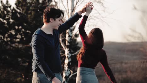 lovely couple dance rotating pirouette at moody sunset on a mountain and having fun