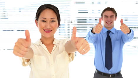 Business-people-looking-at-camera-and-showing-thumbs-up