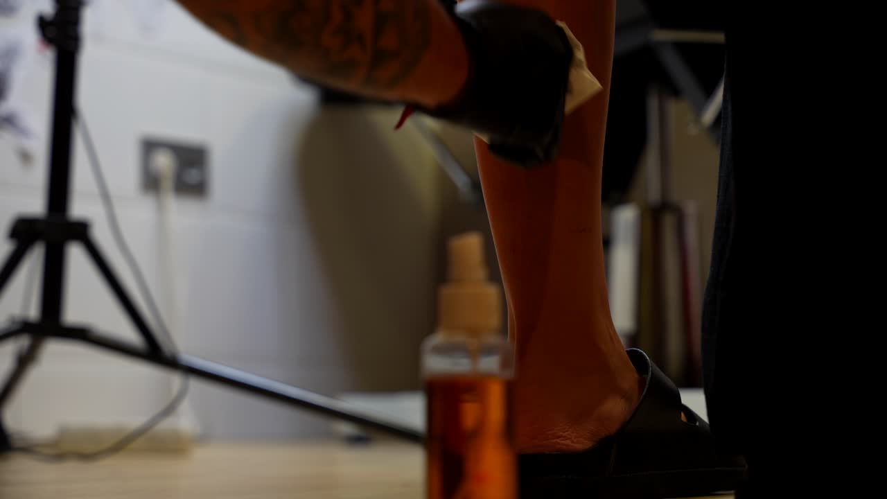 Artist wiping and cleaning the skin before creating a calf tattoo