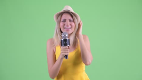 fotografía de estudio de una joven turista bailando y cantando al micrófono contra un fondo verde
