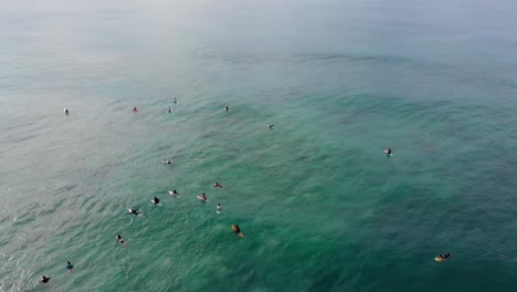 aerial drone view of surfers wading and chilling on surfboards in ocean in sri lanka