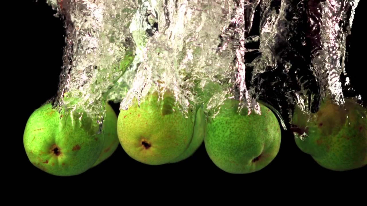 Pere verdi che cadono e schizzano in acqua limpida con bolle
