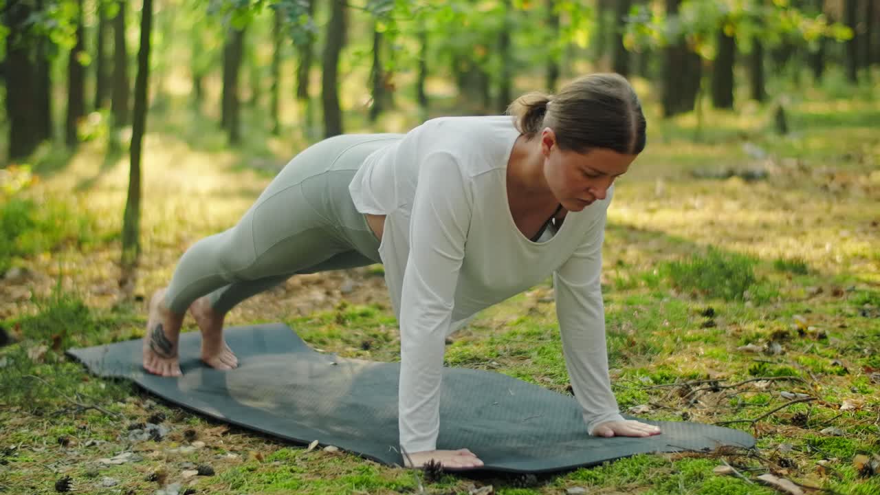 Woman doing yoga plank exercise in forest