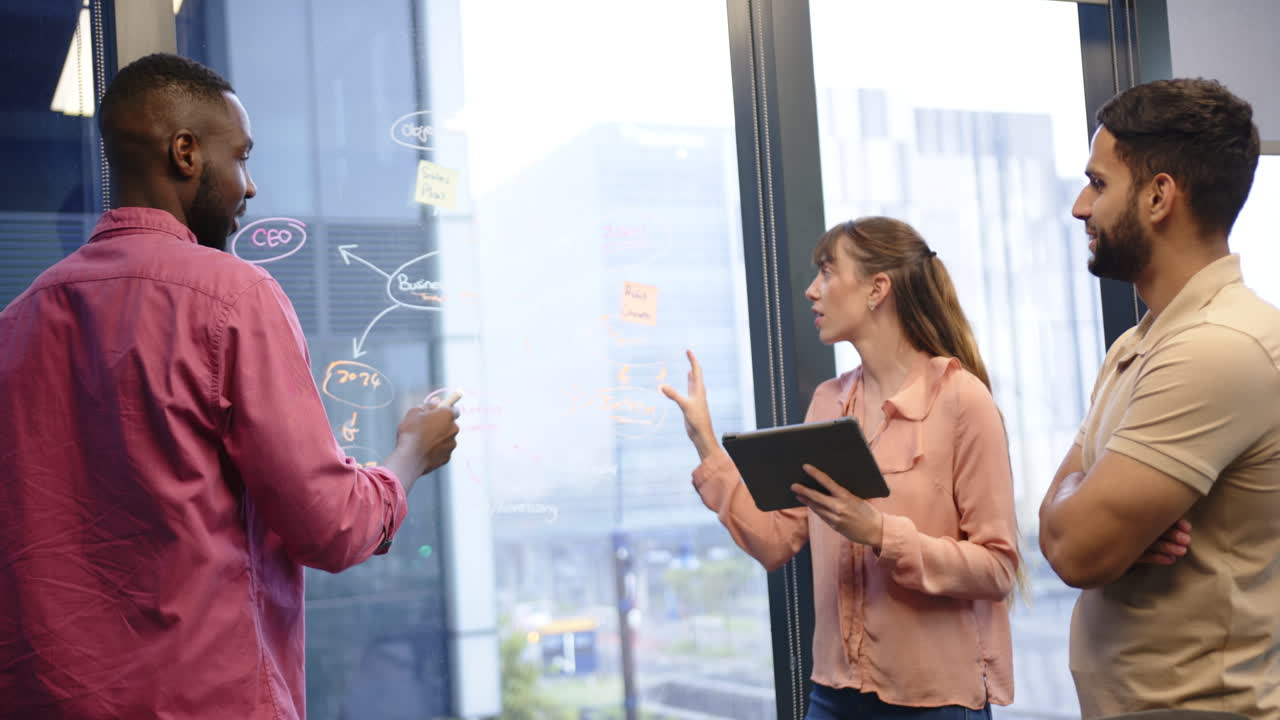 Discussing project strategy, team collaborating with tablet and whiteboard in office