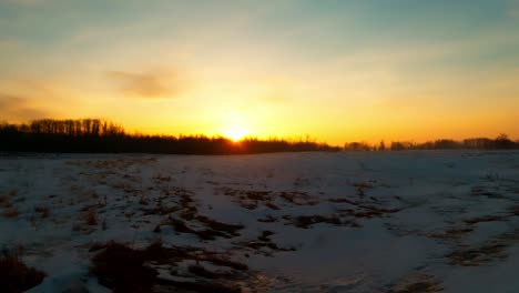 The-Sunrises-glows-in-center-view-in-a-winter-horizon-melt-down-as-the-reflection-has-an-amber-lighting-spreading-from-the-middle-frame-to-the-bottom-while-clouds-above-dissipate-in-time-lapse-motion