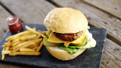 hamburguesa y papas fritas con ketchup en un tablero de pizarra