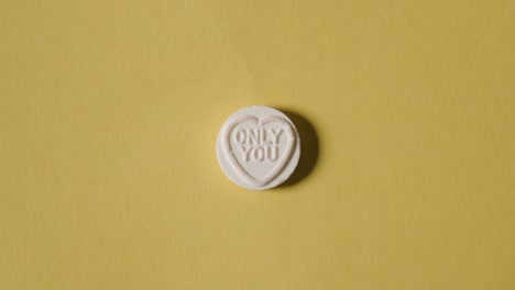 Hand-Picking-Up-Heart-Candy-With-Only-You-Message-On-Yellow-Background