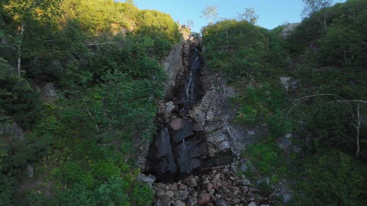 Drone captures a breathtaking waterfall and colorful foliage at golden hour