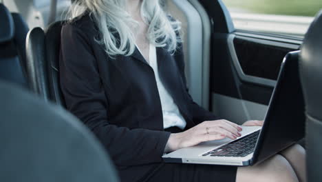 businesswoman using laptop inside the moving car