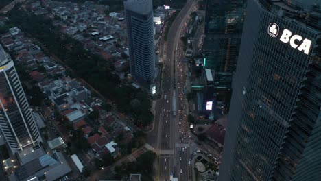 aerial tilting view following busy multi lane traffic into the modern city with tall skyscrapers in jakarta, indonesia