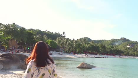 girl walks along the beach with stones and sun beds