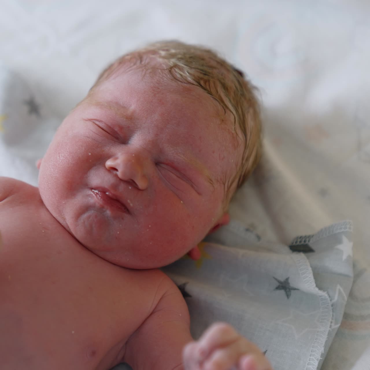 Just born Caucasian baby is unhappy and waving hands. Medic measures newborn's head with a measuring tape. Close up