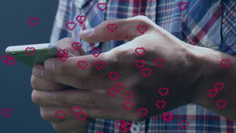 animation of red hearts over caucasian man using smartphone