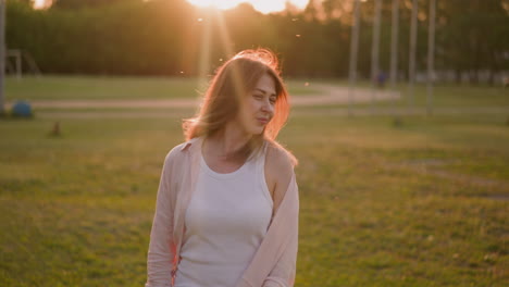 smiling lady in unbuttoned shirt shakes loose hair on field