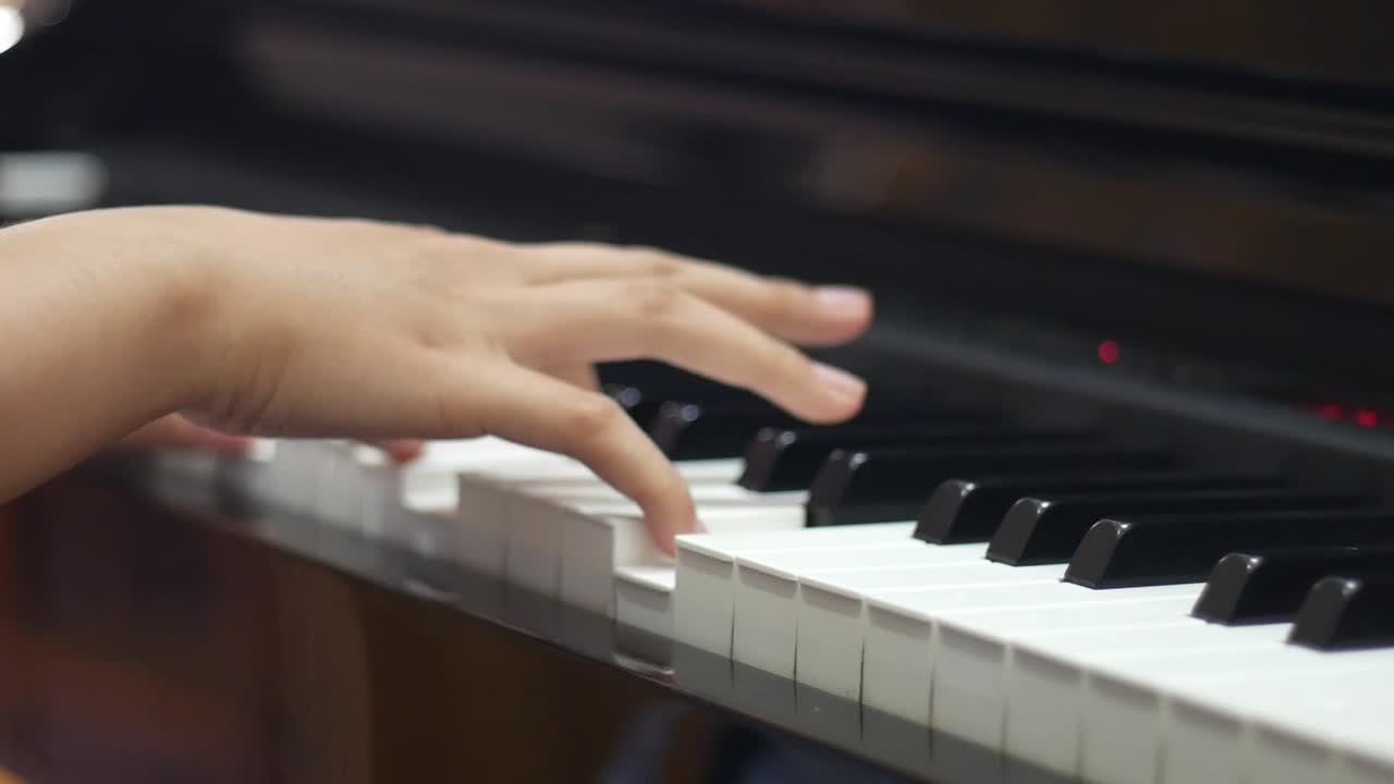 Close up footage of a girl's hand plays a piano. Side view
