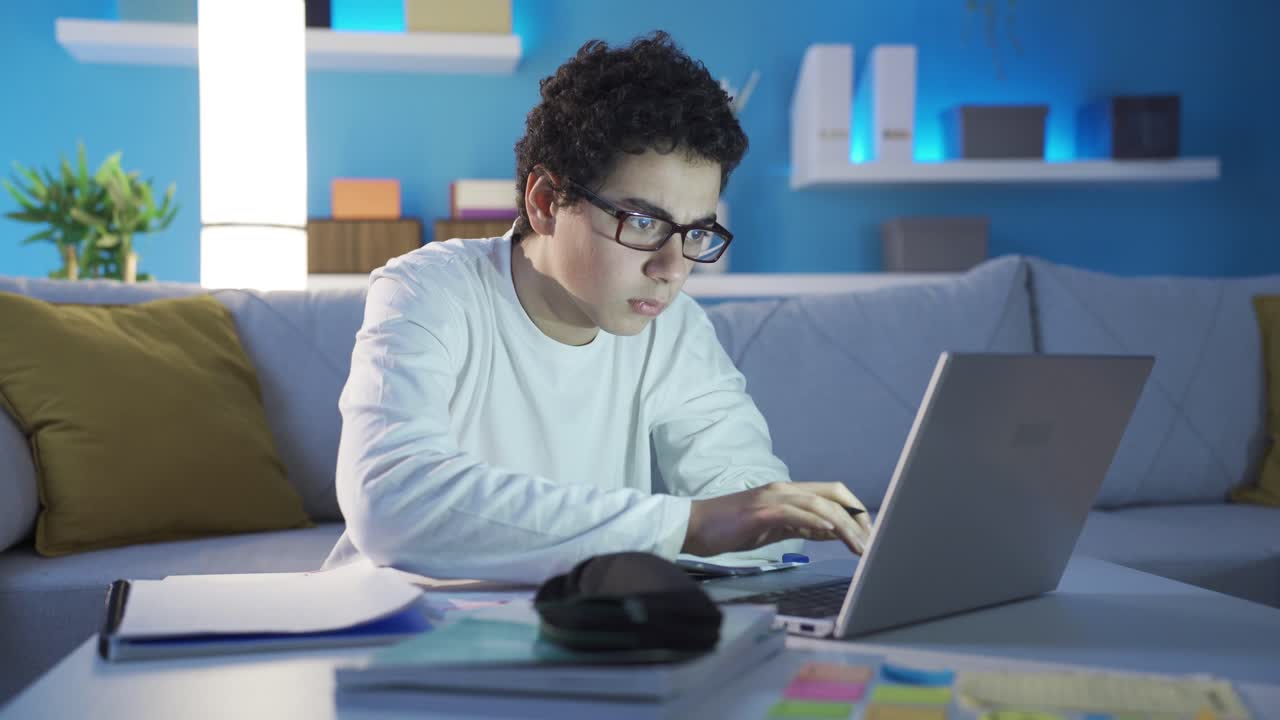 똑똑하고 성공적인 남성 학생이 늦은 밤에 집에서 공부하고 있습니다.