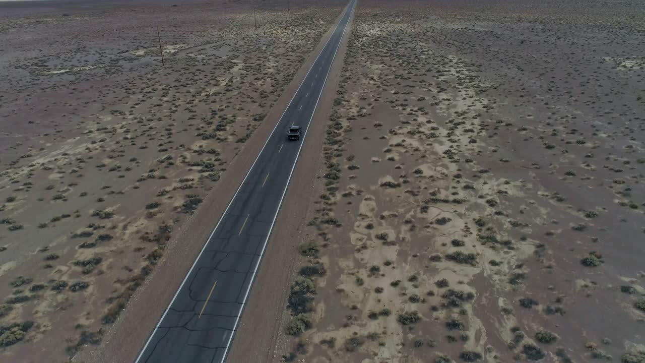 직선적이고 좁은 사막 고속도로에서 멀리 운전하는 트럭의 느린 동작, 높은 하향 조감도