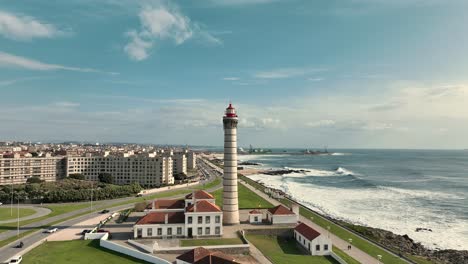 Aerial-view-over-the-lighthouse-of-Leça-da-Palmeira,-Matosinhos-with-the-city-and-coastline-behind