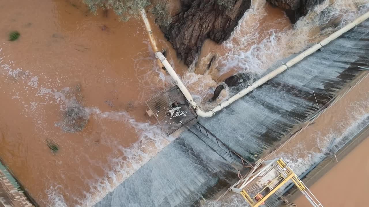 aguas de inundación cayendo en cascada sobre un muro de presa desde un dron 7