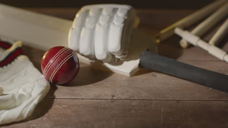 cricket stilleven met close-up van bat ball handschoenen stumps jumper en bails liggen op houten oppervlak in de kleedkamer