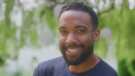 Retrato-De-Cabeza-Y-Hombros-De-Un-Hombre-Sonriente-Y-Relajado-Parado-En-El-Jardín-De-Casa-Después-De-La-Jubilación