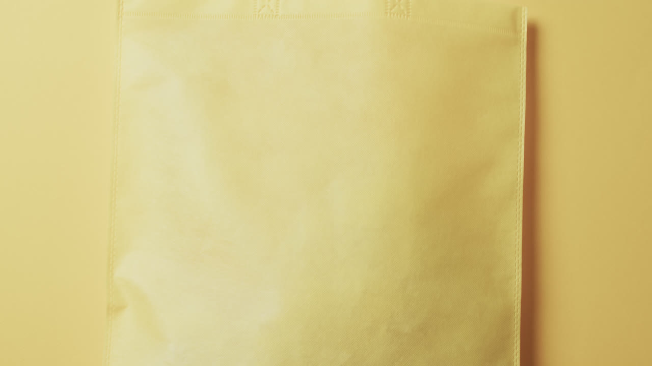 노란색 배경에 복사 공간이 있는 노란색 캔버스 가방의 비디오