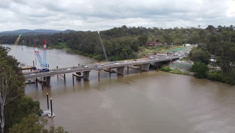Drone flying towards a new bridge construction site over a river