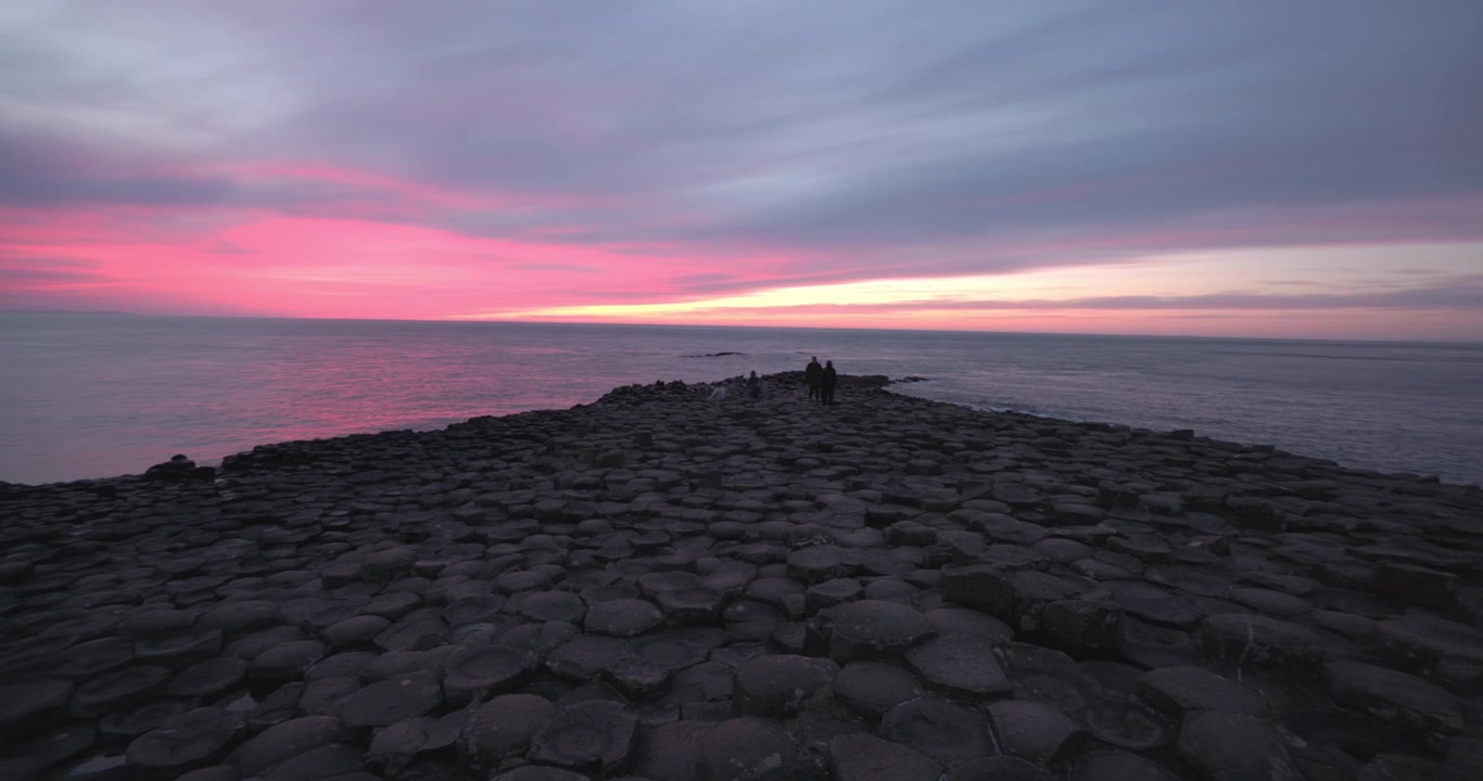 Tomada panorâmica lenta de um pôr do sol vibrante acontecendo sobre a Calçada dos Gigantes.