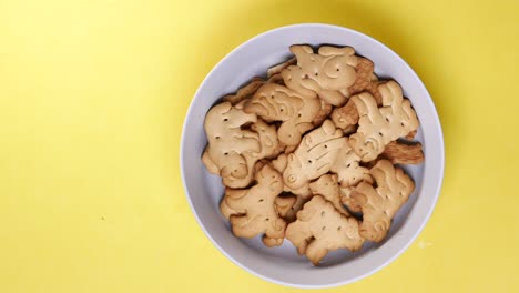 Animal-shape-sweet-cookies-in-a-white-bowl-on-yellow