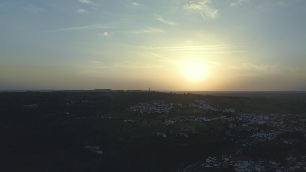 aerial shot European small village Montargil flying over fantastic landscape at colored sunset and yellow big sun and some clouds in front