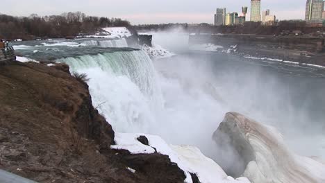 a longshot of niagara falls in winter with tourist hotels in the distance