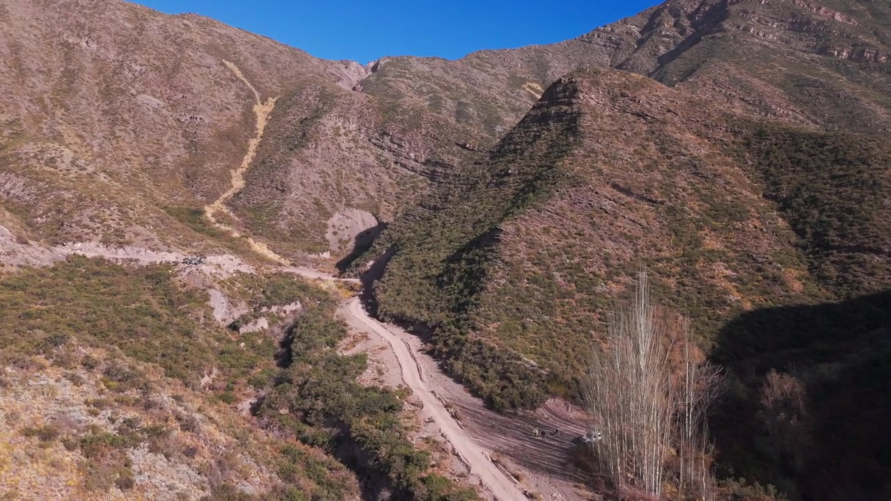 Drone in volo sopra una collina in mezzo a montagne erbose con una strada in Argentina.