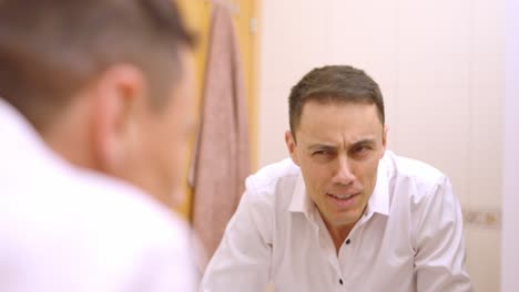 businessman checking his hair in bathroom mirror