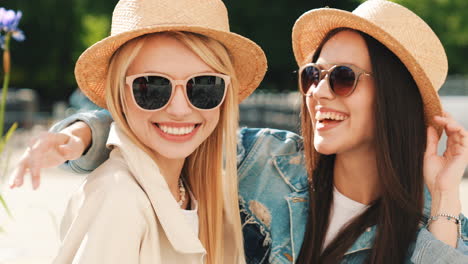 two happy women posing in straw hats and sunglasses